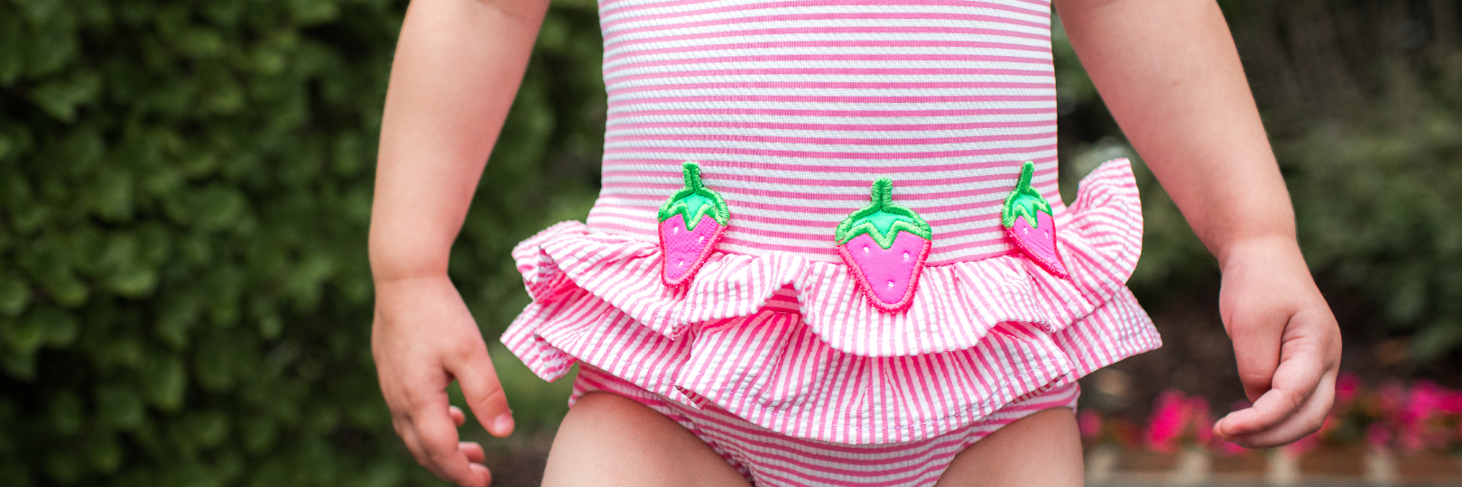 Close up of girl wearing pink seersucker swimsuit with strawberries