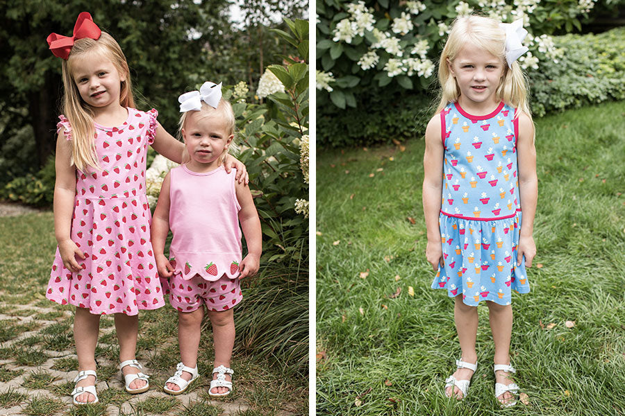 two images, one with two girls in pink strawberry outfits and the other with one girl wearing a blue potted blooms print dress