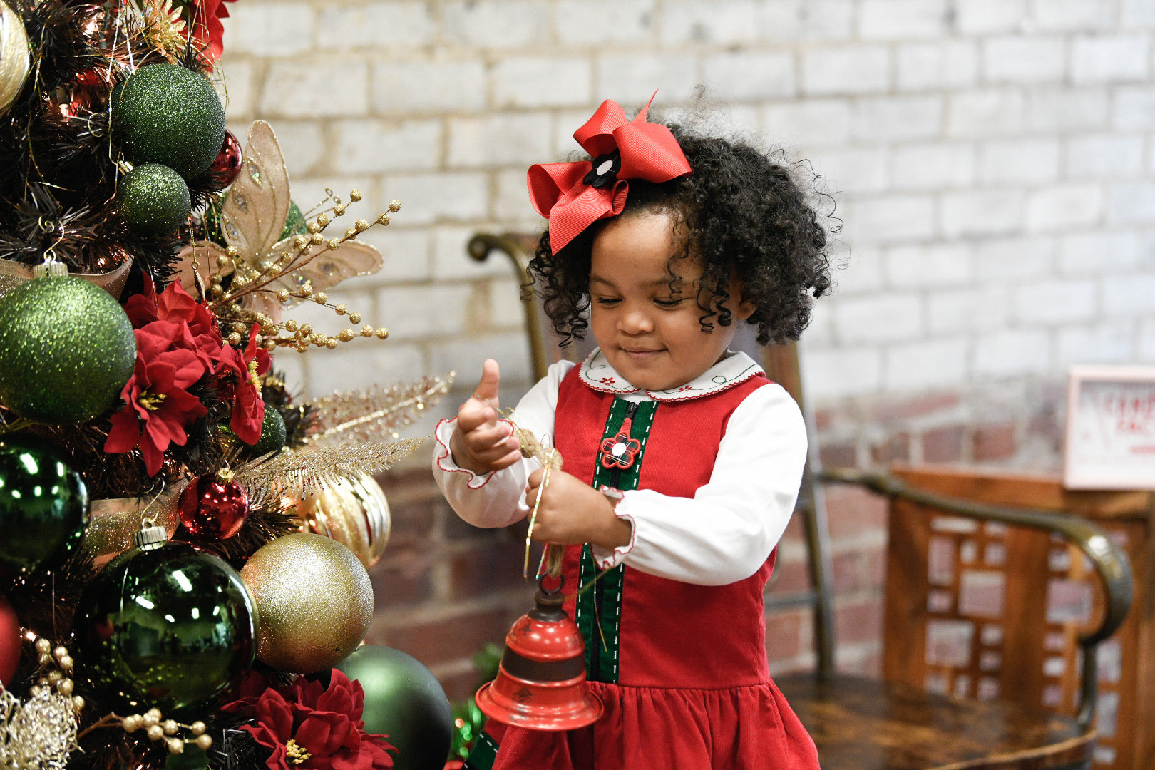 young girl decorating a tree in a holiday dress with matching hair bow