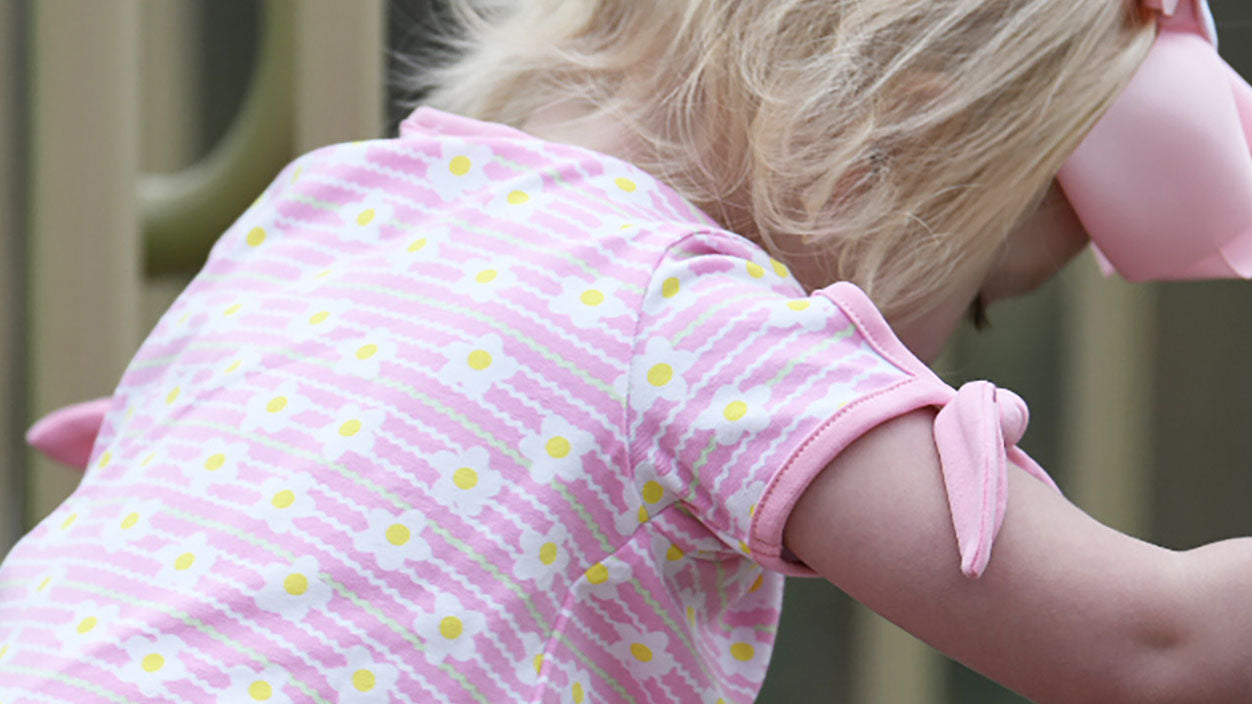 close-up of a young girl in ric rac floral print dress playing