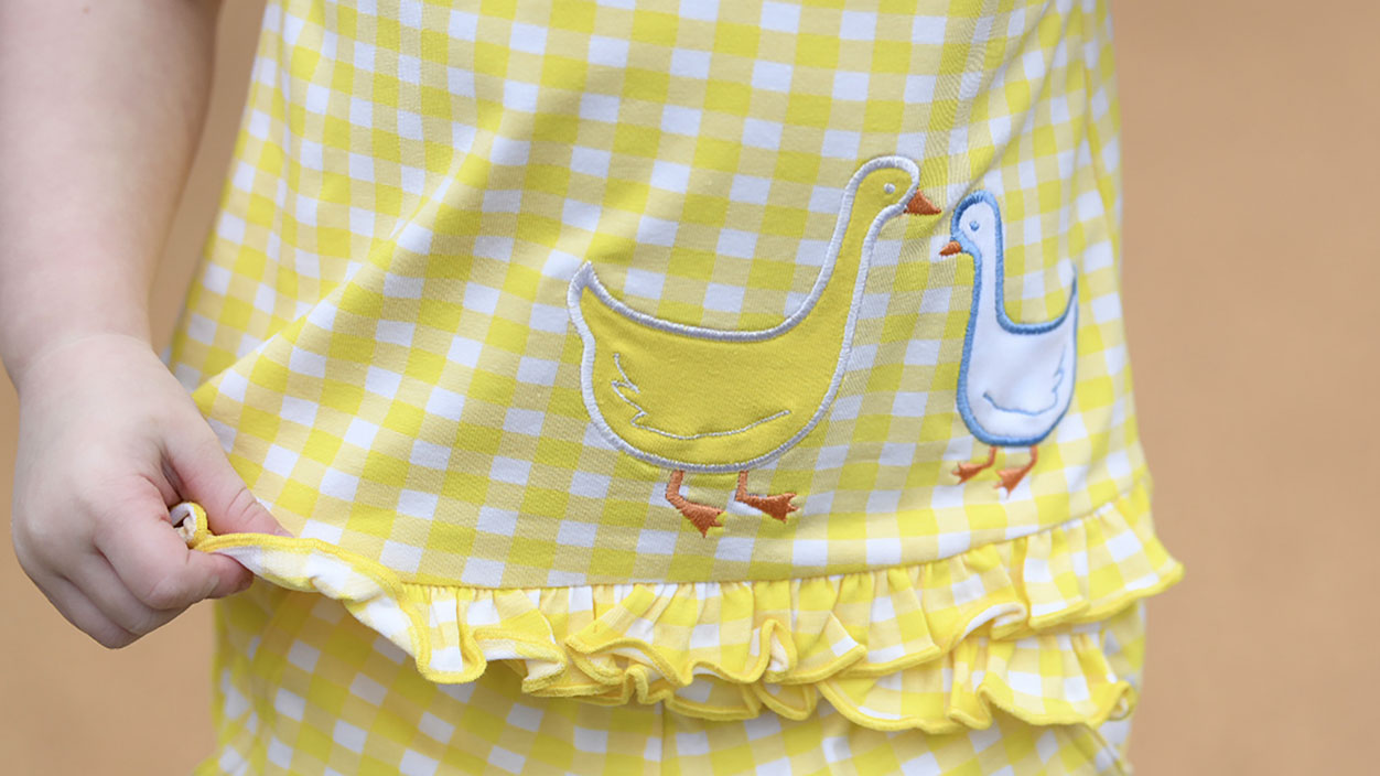 close-up of a young girl in a yellow gingham outfit