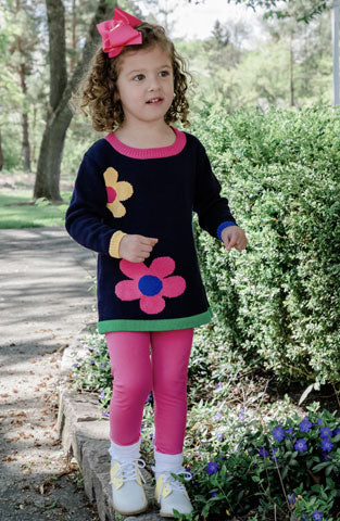 young girl outside in navy sweater with large flowers and pink leggings