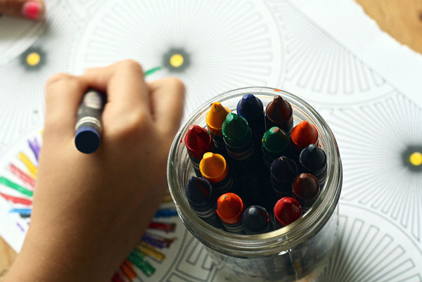 the hand of a child coloring with crayons on paper