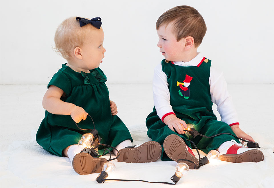 two toddlers in green velvet holiday outfits