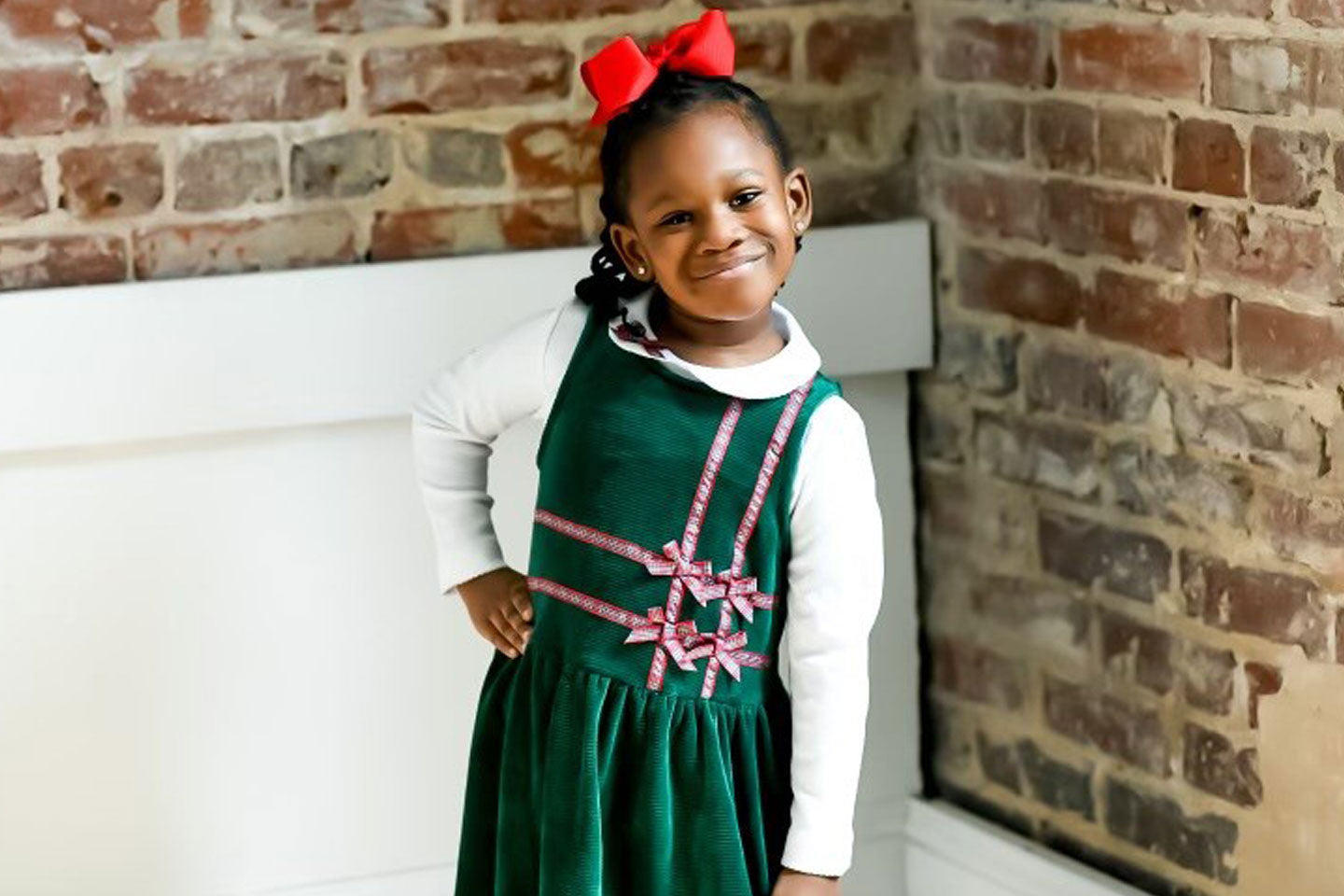 young girl wearing green velvet dress with red plaid bows