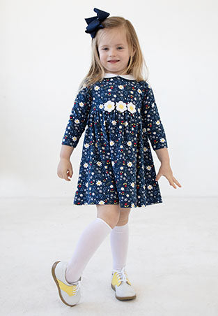 young girl in a navy floral dress, stockings and saddle shoes
