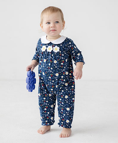 toddler girl in a navy floral longall holding a pop-it