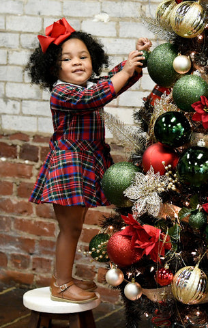 young girl in a plaid dress decorating a tree
