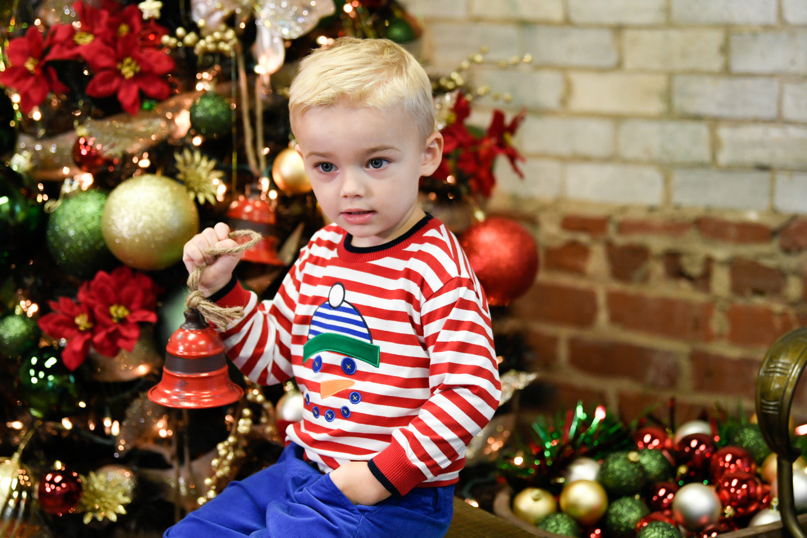 boy holding ornament wearing red and white stripe shirt with snowman